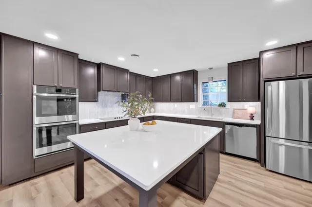 a kitchen with kitchen island a refrigerator stove microwave and cabinets