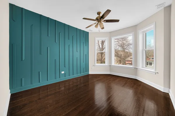 a view of empty room with wooden floor and fan