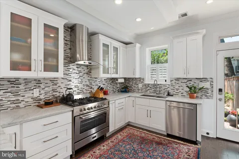 a kitchen with stainless steel appliances kitchen island granite countertop a stove and white cabinets