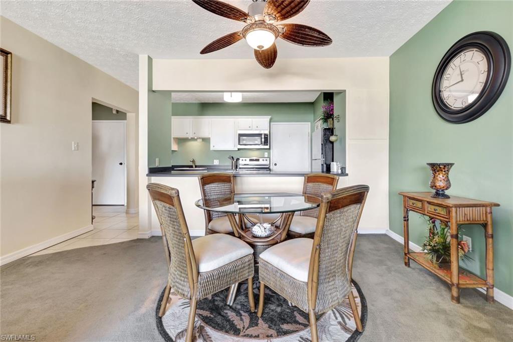 60 West Pelican Street, Unit 401 Naples, FL 34113 - Photo 17 of 31 a dining room with furniture and a chandelier fan