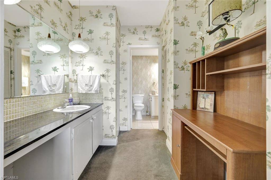 60 West Pelican Street, Unit 401 Naples, FL 34113 - Photo 22 of 31 a bathroom with a granite countertop sink a large mirror and a shower