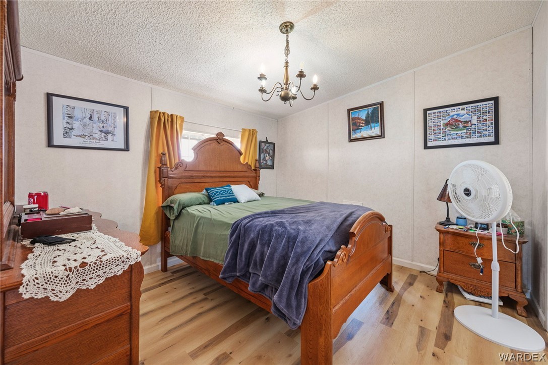 2465 Egar Road Golden Valley, AZ 86413 - Photo 28 of 98 The property features a bedroom with light wood flooring, a ceiling-mounted light fixture, and a window with yellow curtains