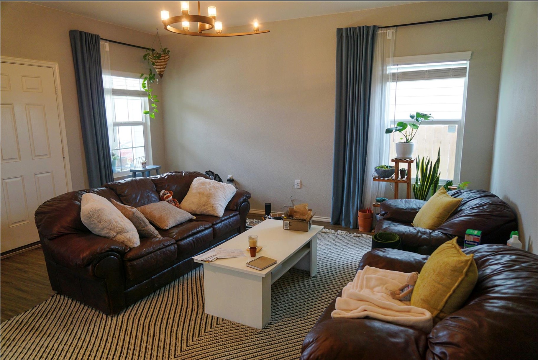 2321 Forgetmenot Lane Manor, TX 78653 - Photo 7 of 27 A warm living room with a striking chandelier, rich brown seating, and natural light flowing through the windows.