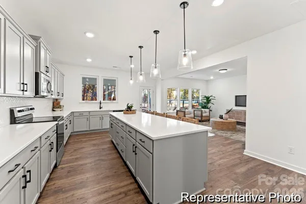 a large kitchen with kitchen island a sink a counter top space appliances and cabinets