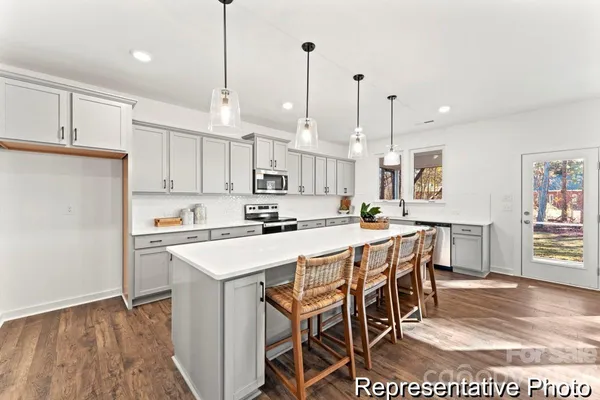 a kitchen with stainless steel appliances granite countertop a sink a stove a refrigerator and white cabinets with wooden floor