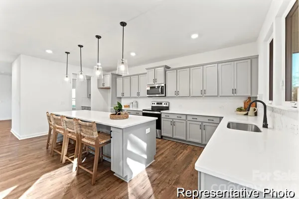 a kitchen with kitchen island granite countertop a sink a counter space appliances and cabinets