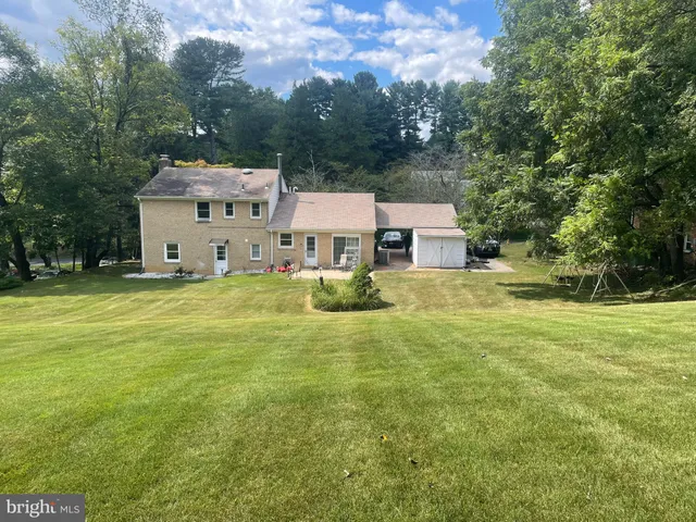 a view of a house with a big yard and large trees