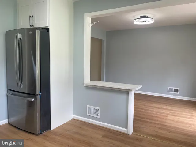 a view of a refrigerator in kitchen and an empty room