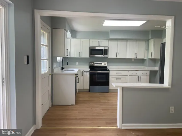 a kitchen with stainless steel appliances granite countertop a stove top oven a sink and white cabinets