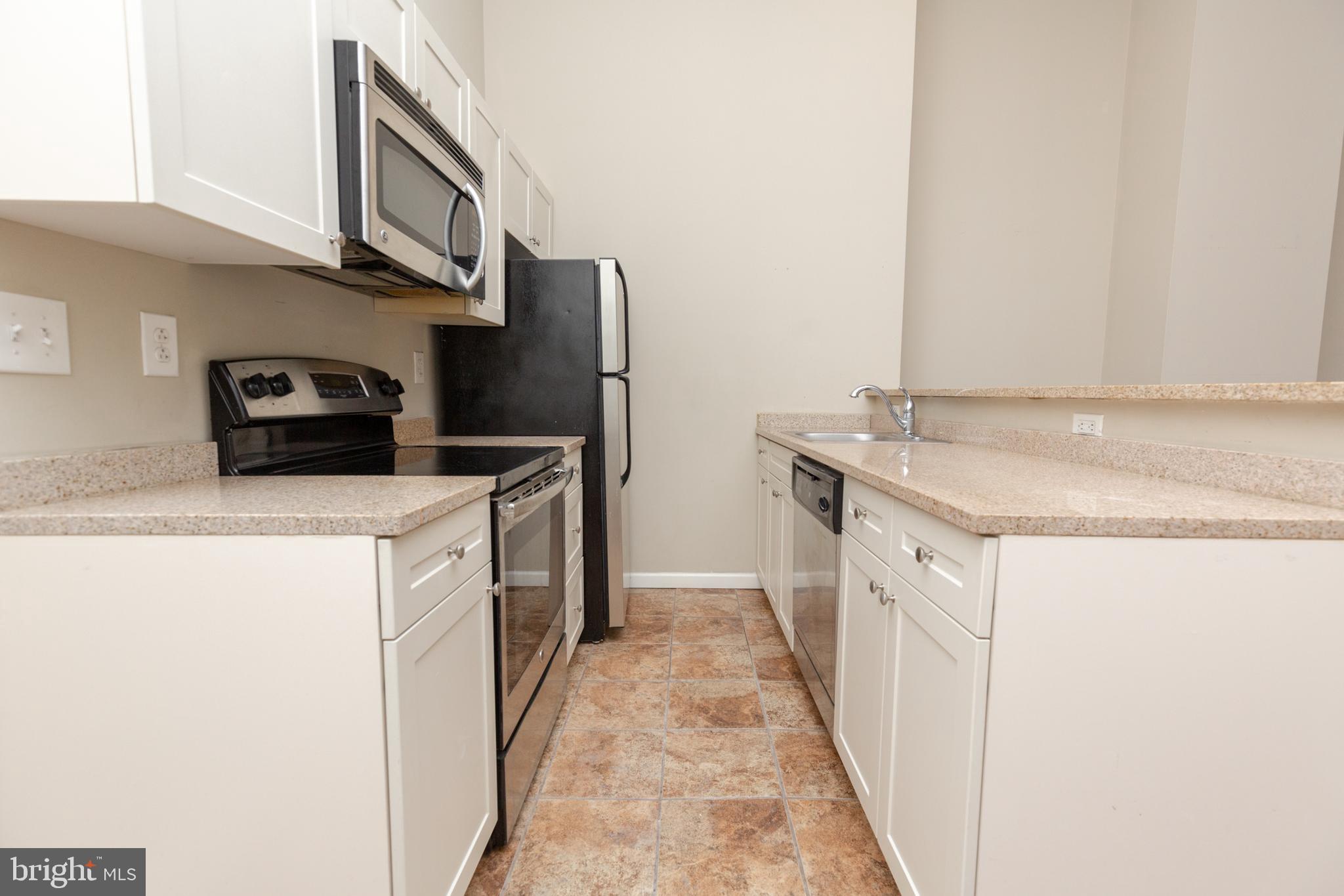 1411-2 Walnut Street, Unit 312 Philadelphia, PA 19102 - Photo 8 of 23 a kitchen with stainless steel appliances granite countertop a refrigerator and a stove