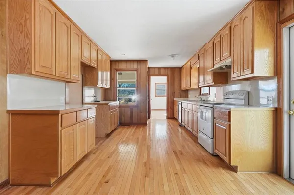 a kitchen with granite countertop wooden floors white cabinets and stainless steel appliances