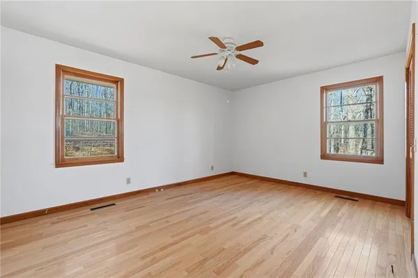 an empty room with wooden floor and windows