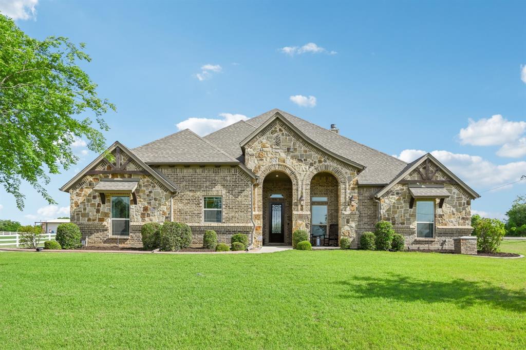 French provincial home with stone siding, brick siding, and a front yard