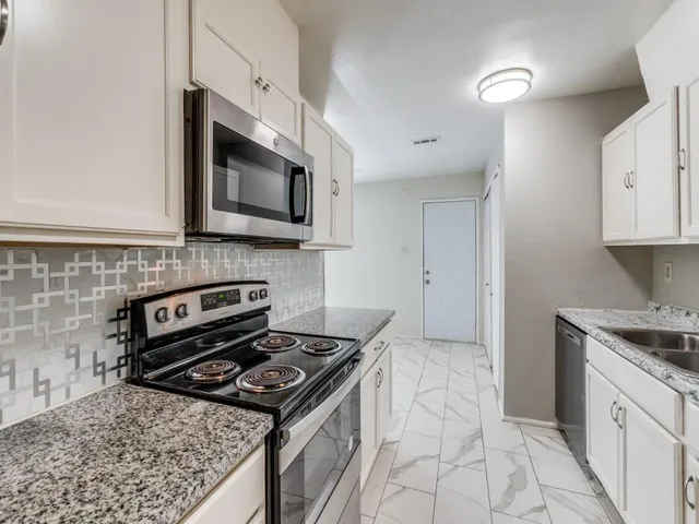 a kitchen with stainless steel appliances granite countertop a stove a microwave and a sink