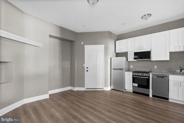 a view of kitchen with granite countertop stainless steel appliances and wooden floor