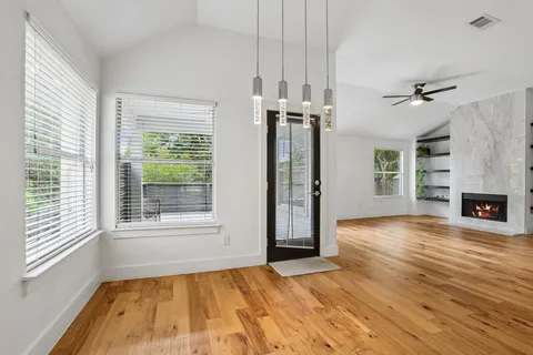 wooden floor in an empty room with a fireplace and a window