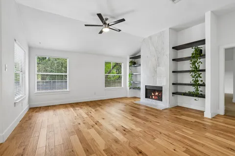 a view of a livingroom with wooden floor a fireplace and windows