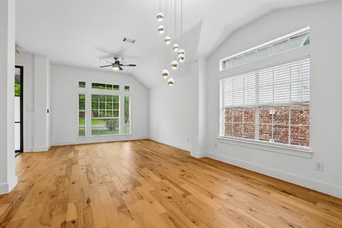 a view of an empty room with a window and wooden floor