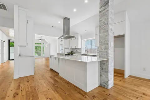 a kitchen with stainless steel appliances a sink a stove a refrigerator and white cabinets