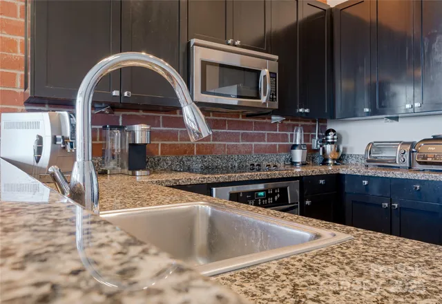 a kitchen with stainless steel appliances granite countertop a stove a sink and a microwave