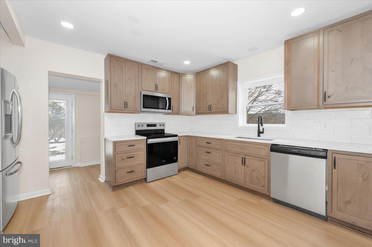 9932 Kelly Road Frederick, MD 21701 - Photo 21 of 74 a large white kitchen with stainless steel appliances granite countertop a stove a sink a refrigerator and white cabinets with wooden floor