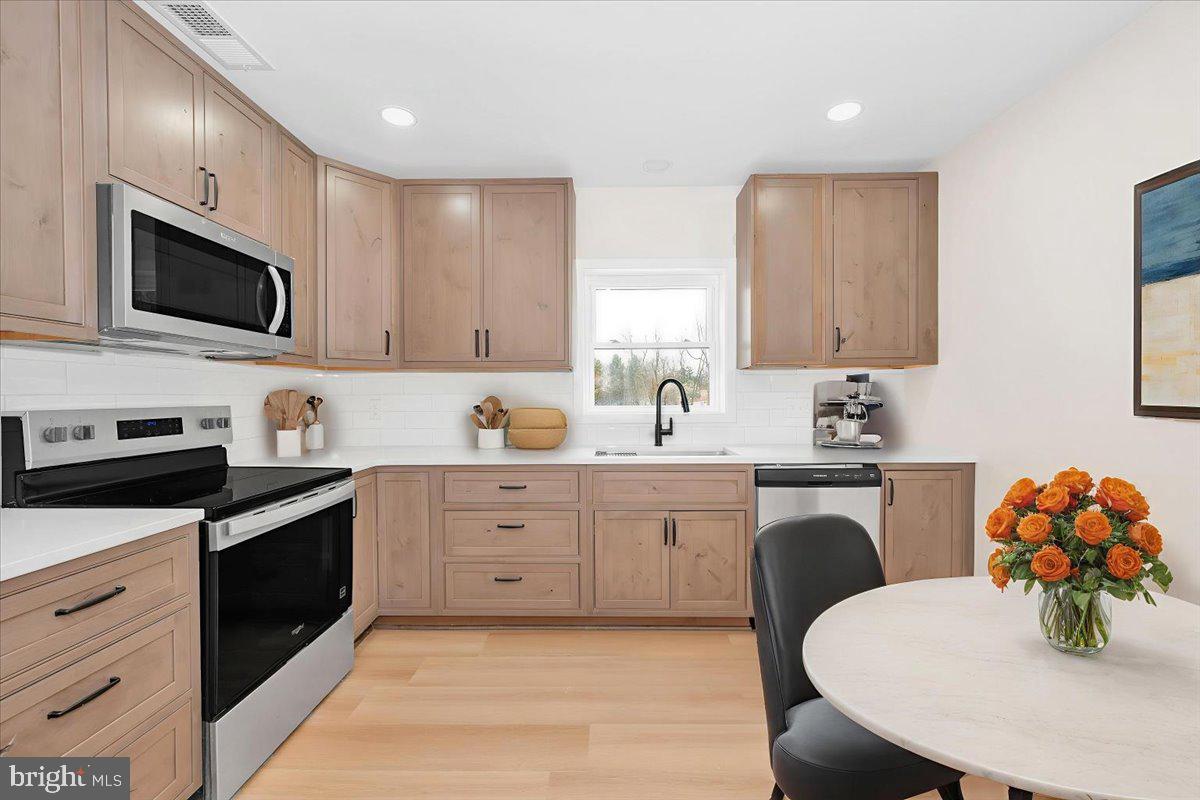9932 Kelly Road Frederick, MD 21701 - Photo 68 of 74 a kitchen with stainless steel appliances white cabinets a sink a stove a microwave and dining table