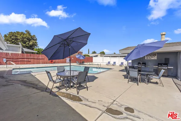 a view of a house with pool fire pit a patio and a yard