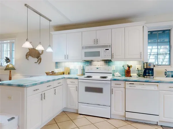 a kitchen with white cabinets white appliances and sink