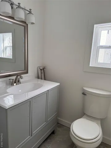 a bathroom with a granite countertop toilet sink and mirror