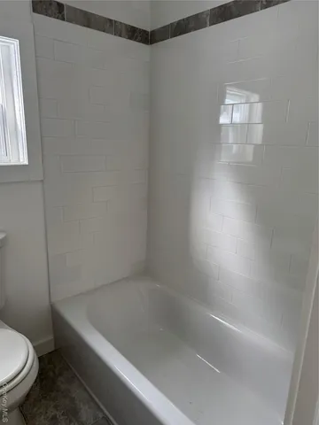 a bath tub sitting next to a white toilet and a shower