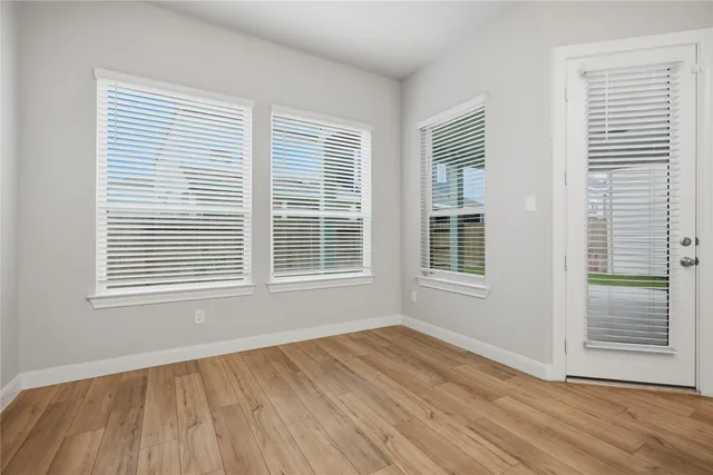 a view of an empty room with a kitchen and wooden floor