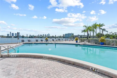 a view of building with lot of cars and trees in the background