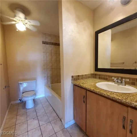 a bathroom with a granite countertop sink a toilet a mirror and bathtub