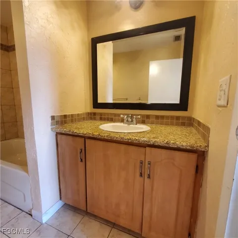 a bathroom with a granite countertop sink and a mirror