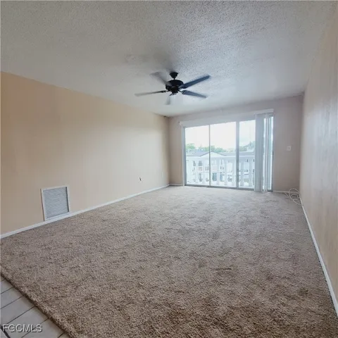 an empty room with windows and ceiling fan