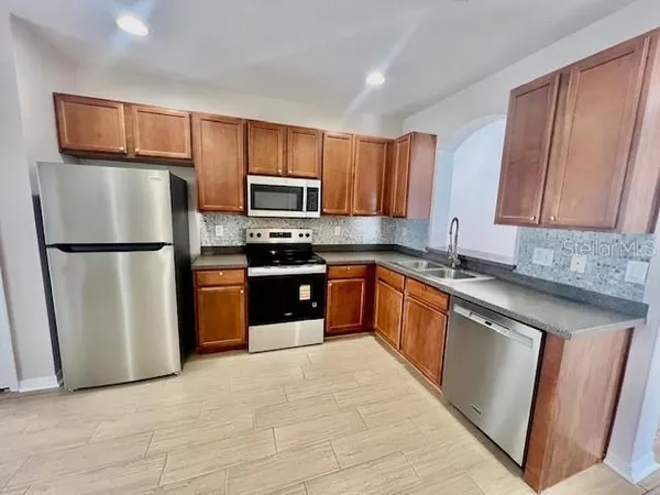a kitchen with stainless steel appliances granite countertop a refrigerator stove a sink dishwasher and microwave