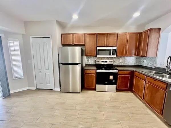 a kitchen with stainless steel appliances granite countertop a refrigerator a stove a sink and a microwave