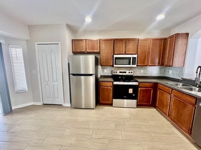 15633 Stable Run Drive Spring Hill, FL 34610 - Photo 12 of 50 a kitchen with stainless steel appliances granite countertop a refrigerator a stove a sink and a microwave