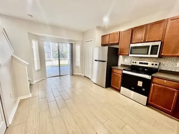 a kitchen with stainless steel appliances a stove a refrigerator a sink a microwave a counter top space and cabinets