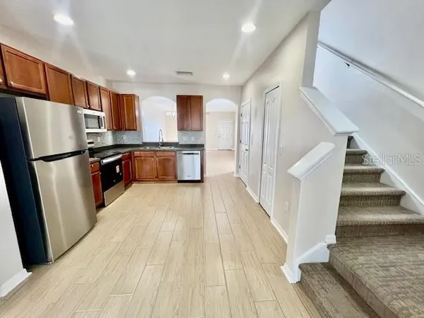 a kitchen with stainless steel appliances granite countertop a refrigerator a stove a sink and a microwave