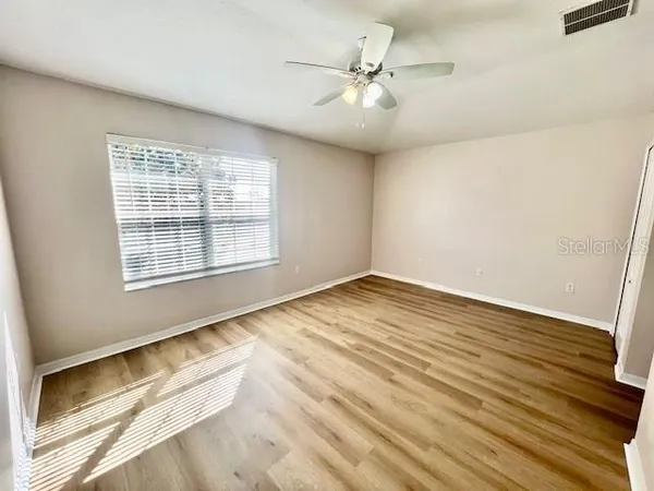 a view of an empty room with wooden floor and a window