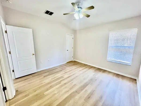 a view of an empty room with wooden floor and a window
