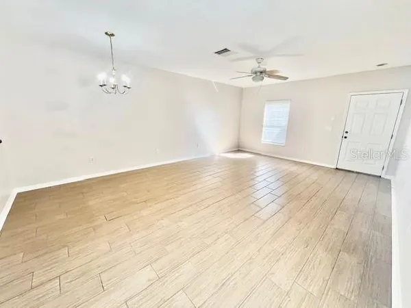 an empty room with wooden floor ceiling fan and window