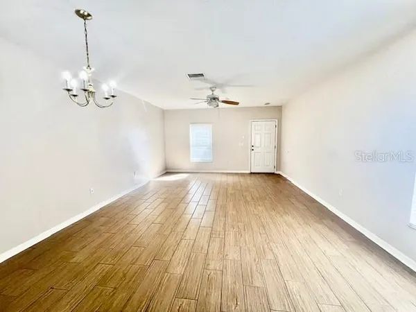 a view of empty room with wooden floor and ceiling fan