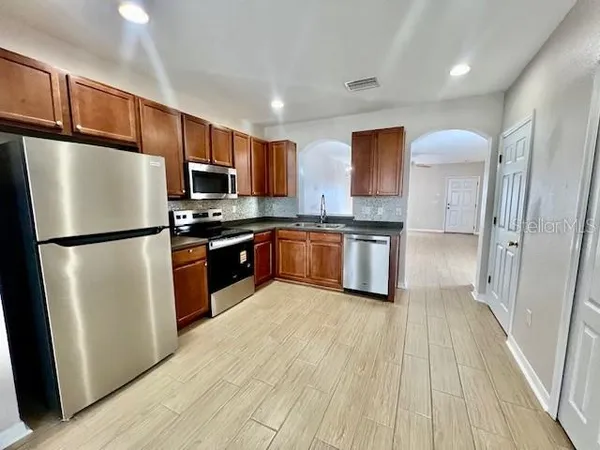 a kitchen with stainless steel appliances granite countertop wooden cabinets a refrigerator a sink and a stove