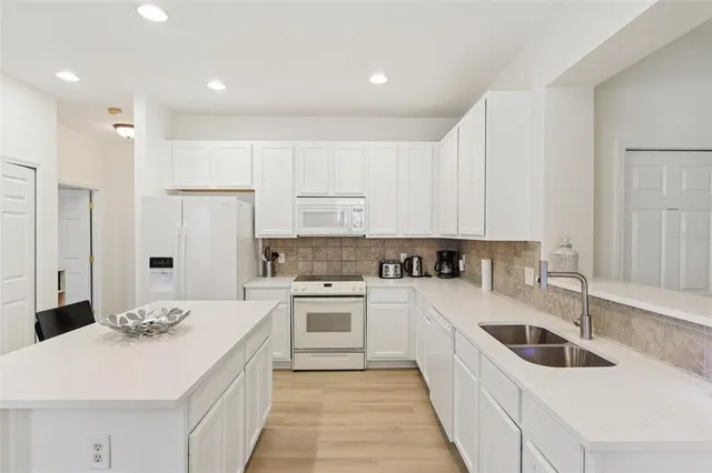 a kitchen with white cabinets and white appliances
