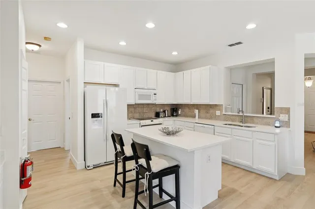 a kitchen with a sink a refrigerator and white cabinets