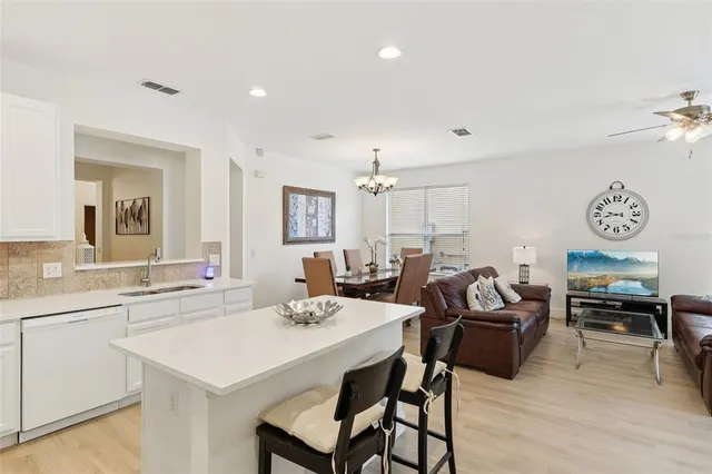 a view of a dining room and livingroom with furniture wooden floor a rug a chandelier