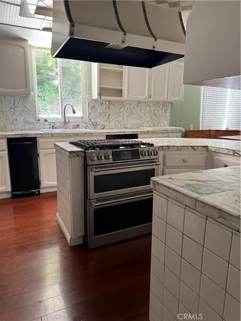 a kitchen with granite countertop a stove a sink and a microwave