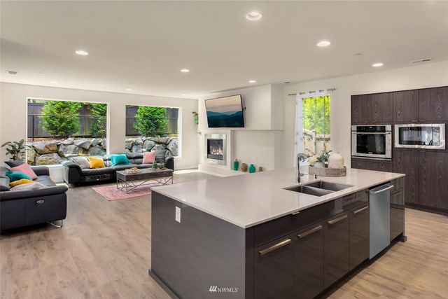 a open kitchen with stainless steel appliances granite countertop a sink dishwasher stove and refrigerator with wooden floor